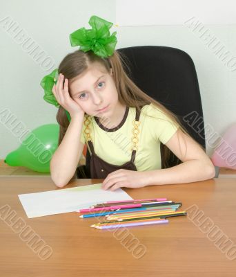Girl sitting at a table with pencils