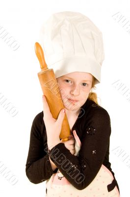 young cook wearing a chefs hat is holding a woorden rolling pin