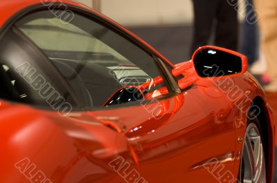 Right side mirror of shiny red car