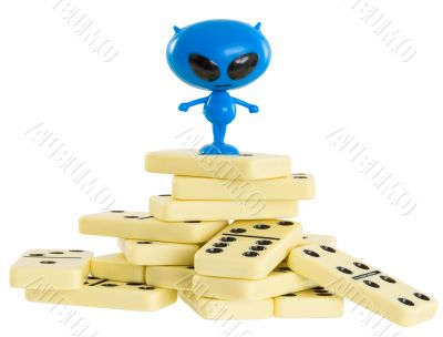 Blue toy alien on a heap from dominoes