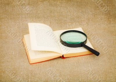 Old book and magnifier glass on canvas