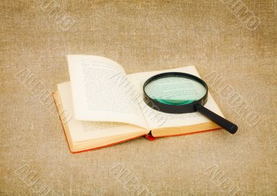 Old book and magnifier glass on canvas Old book and magnifier glass on canvas