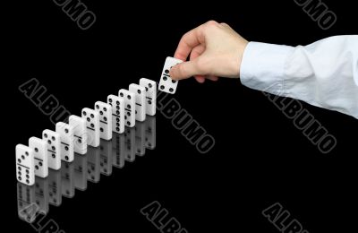 Hand building a line from dominoes on black Hand building a line from dominoes on black