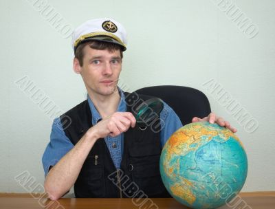Guy in a sea uniform cap with globe and magnifier Guy in a sea uniform cap with globe and magnifier