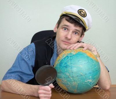 Man in a sea uniform cap with globe and magnifier Man in a sea uniform cap with globe and magnifier