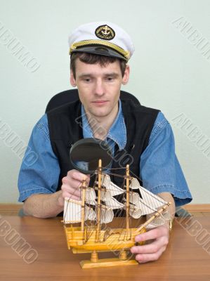 Man with a magnifier and model of a sailing vessel Man with a magnifier and model of a sailing vessel