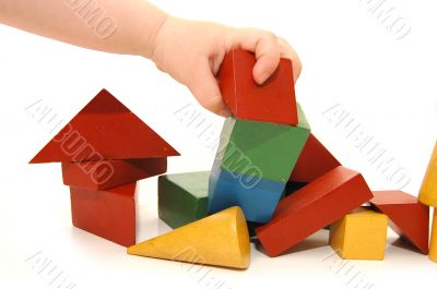 The children`s hand has destroyed construction from cubes