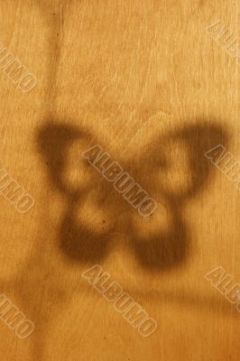 Shade of the butterfly on a wooden yellow wall