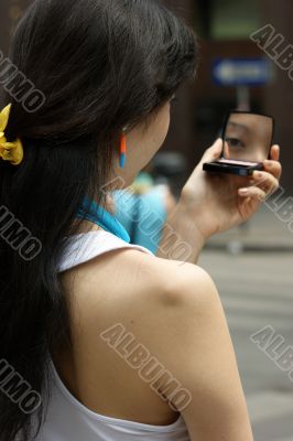 Young Woman with a lipstick mirror on the road.