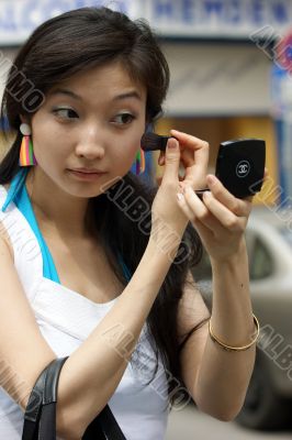 Young Woman with a lipstick mirror on the road.