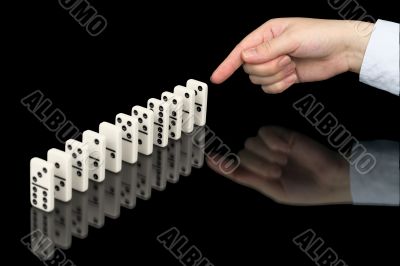 Hand pushing dominoes counters on black Hand pushing dominoes counters on black