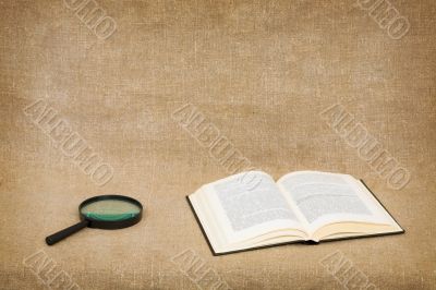 Open book and magnifier on canvas Open book and magnifier on canvas