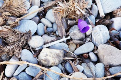 Used syringe on pebbles