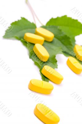 yellow vitamin pills over green leaves