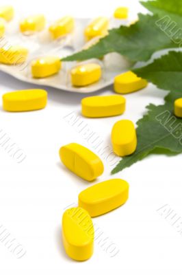 yellow vitamin pills and green leaves