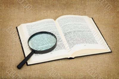 Open book and magnifier against a canvas - a still-life