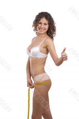 Smiling fit woman with measure tape shows OK
