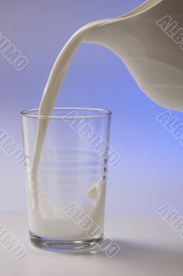 milk pouring in glass from pitcher