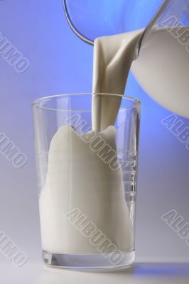 milk pouring in glass from pitcher