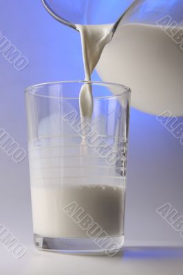 milk pouring in glass from pitcher