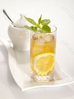 Cold black tea with lemon, ice and water drops on the glass surf