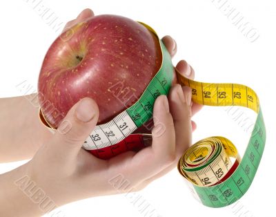 Red apple with tape measure in human hands over white with clipp
