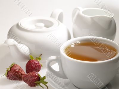 cup of black tea on the table with dishware and strawberry