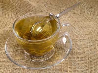 cup of green tea on hessian with honey spoon