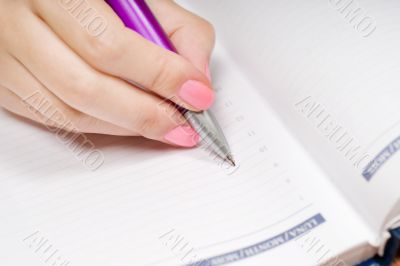 Hand writing in a notebook with pen