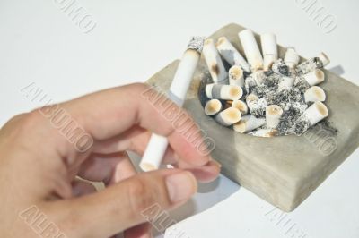 Full ashtray and hand holding cigarette