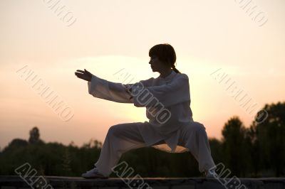 woman in white suit make`s taiji chuan exercise
