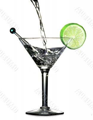 Pouring alcohol in a martini glass with slice of lime