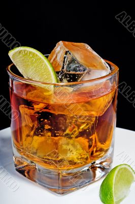 Whiskey in a glass with ice cubes and slices of lime
