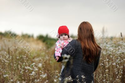 Young mother walking away holding her baby