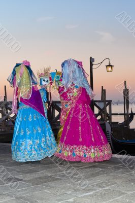 Venice Carnival masks looking at hand mirrors