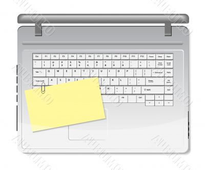 Yellow memo and paper clip on white keyboard
