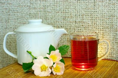 tea with dog-rose flowers and white teapot