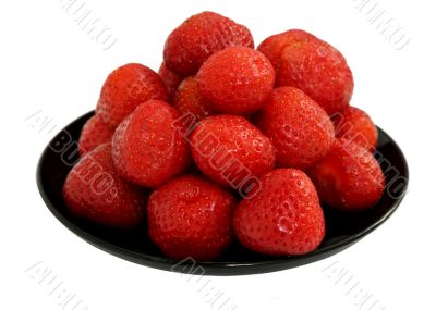 Ripe berries of a strawberry on black saucer