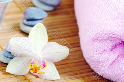 spa with orchids towels and stones on wet wooden background