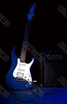 electric guitar and combo amplifier in rays of blue light