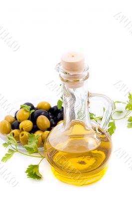 Olives and oil in jug with greens