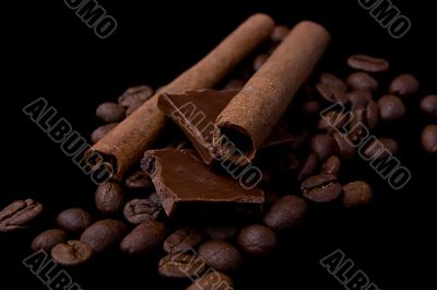 Cinnamon sticks over coffee beans and chocolate