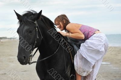 woman mount a  horse on the beach