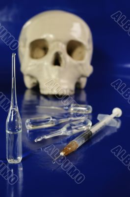 Medical syringe, ampoules and skull 