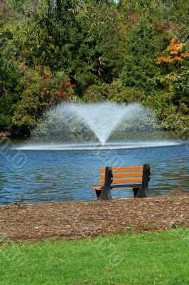 Fountain on a pond with park bench Fountain on a pond with park bench