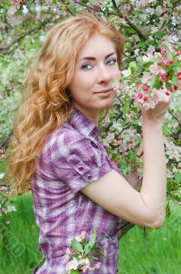 Red-haired woman among apple blossom