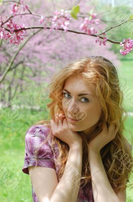 Red-haired woman under viloet flower tree