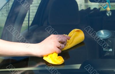 The hand washes a yellow rag the car