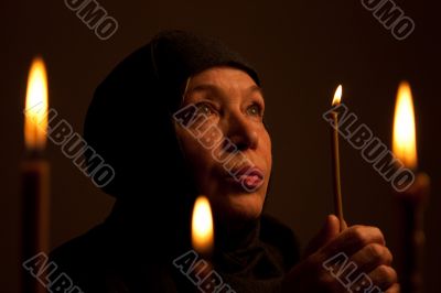 Senior Woman in black clothes with candle.