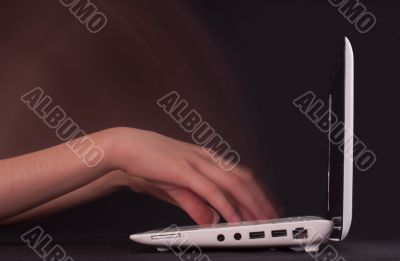 Hands typing in motion on the laptop keyboard